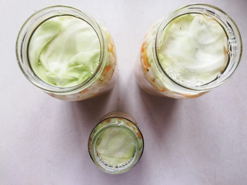 Jars of curtido topped off with salt brine