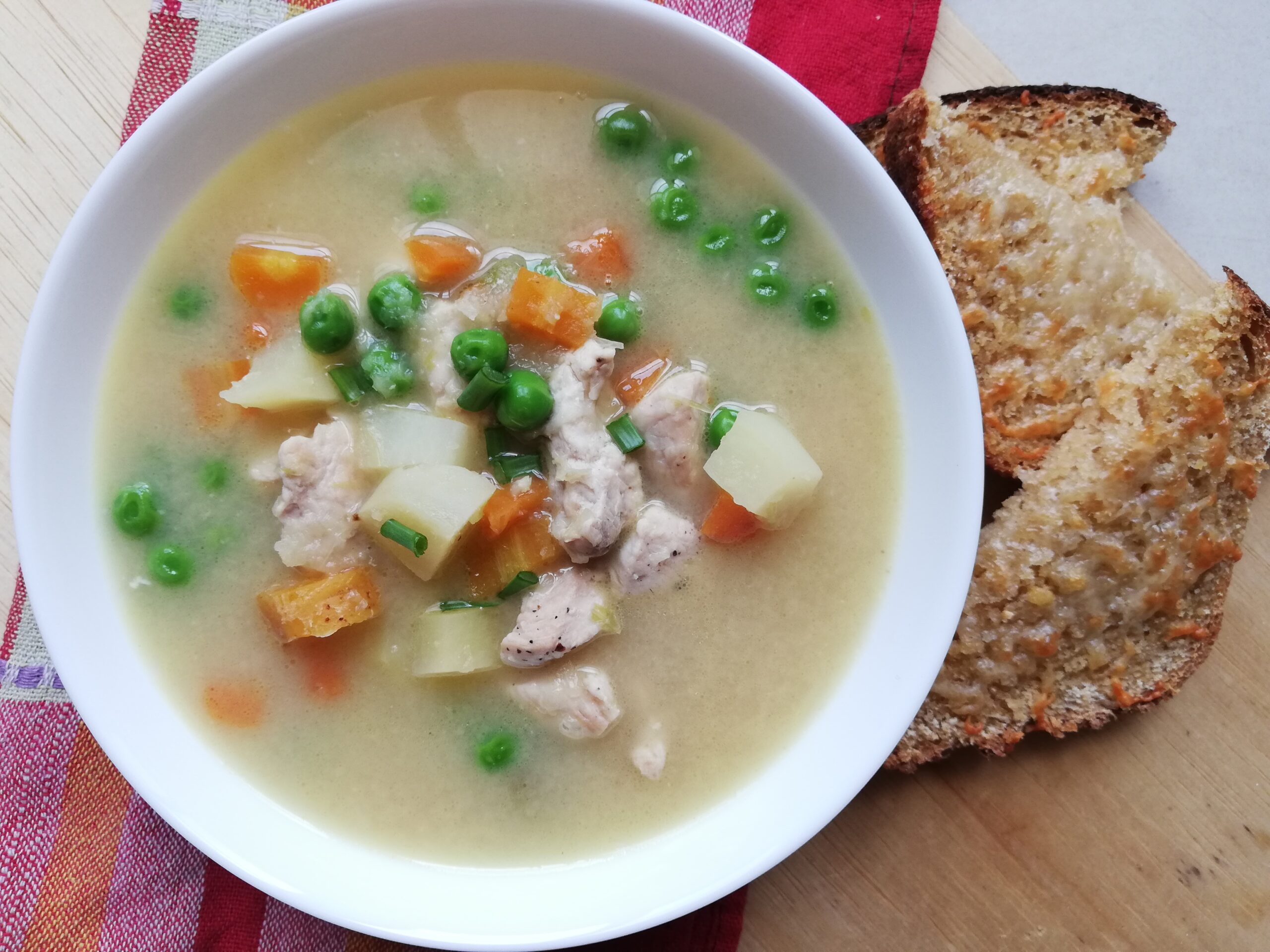 A bowl of chicken pot pie soup with some melted cheese toast on the side