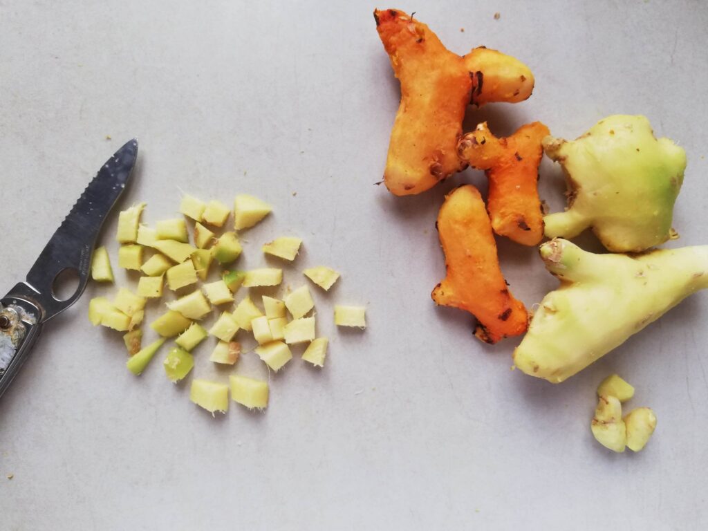 Chopping peeled turmeric and ginger roots with a sharp knife