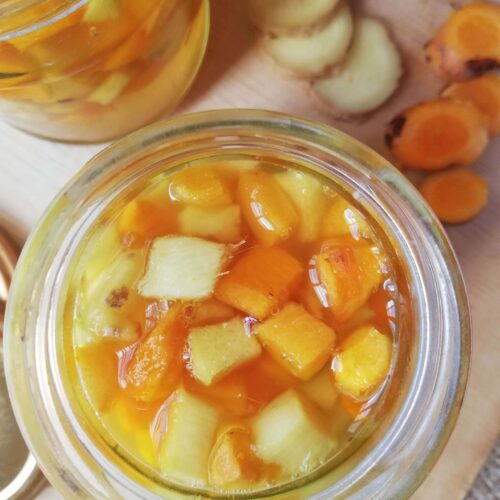 Fresh chopped turmeric and ginger fermenting in glass jars