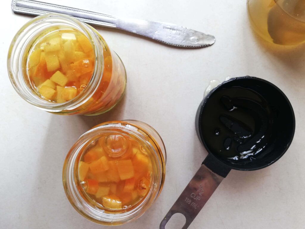 Jars filled with chopped ginger turmeric and raw honey ready to be fermented