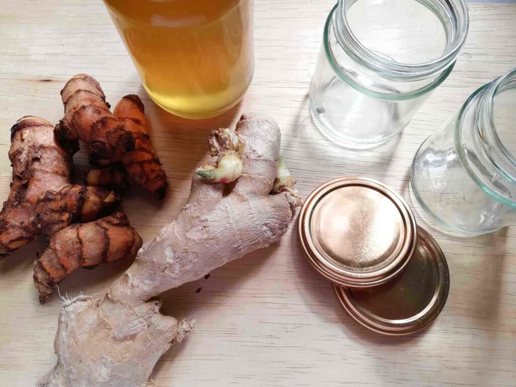 Ingredients for fermented turmeric and ginger honey: jars with lids, fresh turmeric and ginger roots, and a jar of raw honey