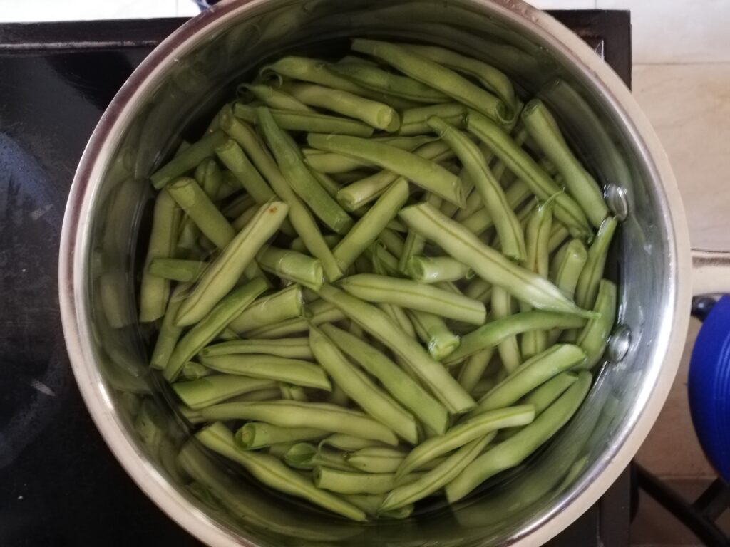 Green beans cooking in water in a small saucepan