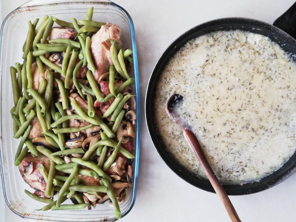 Adding sauteed onions, garlic and risotto rice to chicken, mushrooms and green beans in a glass casserole dish