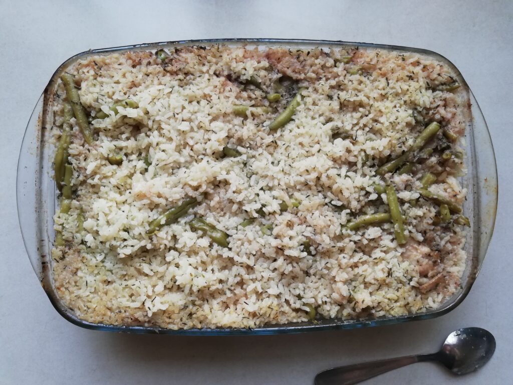 Baked risotto with chicken, mushrooms and green beans in a glass casserole dish, ready to be served
