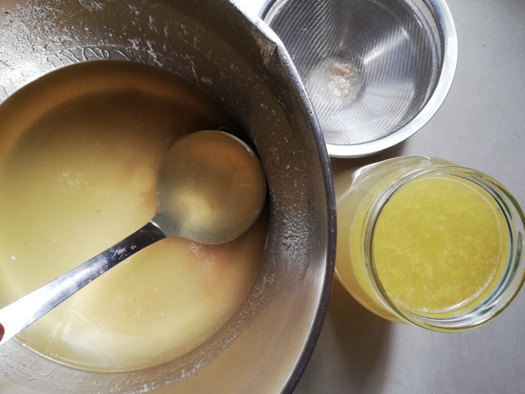 Pouring chicken bone broth into jars