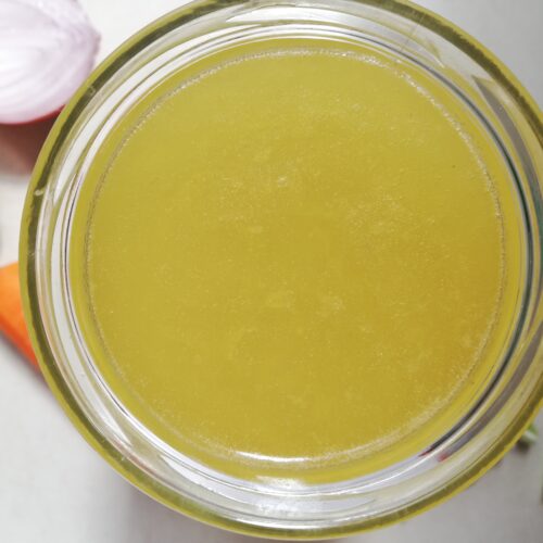 A jar of clear, golden-colored bone broth