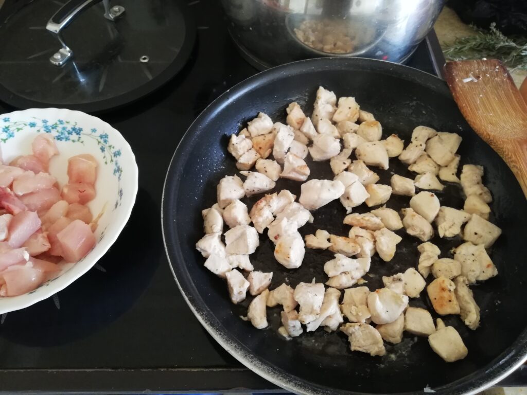 Cubed chicken breast frying in butter in a frying pan
