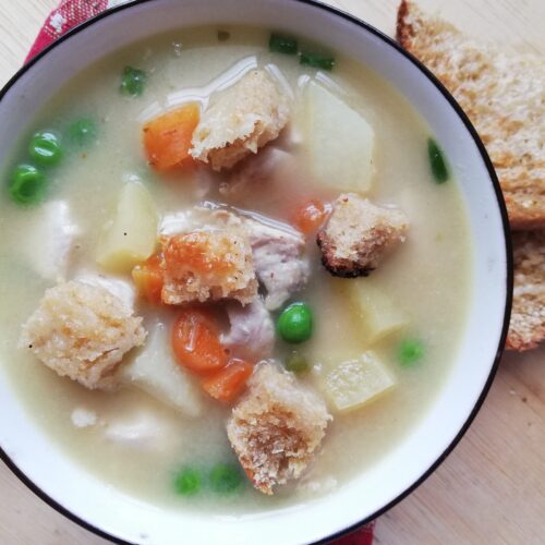 A bowl of hot chicken pot pie soup garnished with chives with some cheese toast on the side