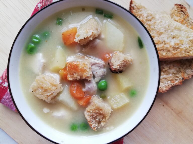 A bowl of hot chicken pot pie soup garnished with chives with some cheese toast on the side