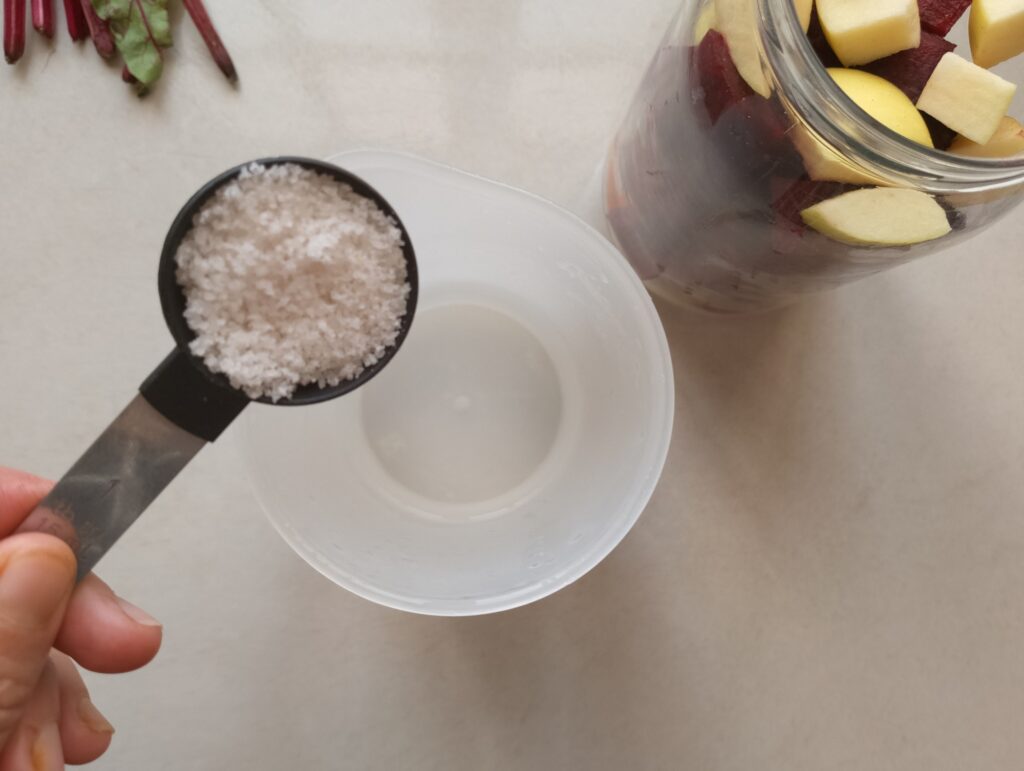 Adding unrefined salt to water to make brine forbeet and apple kvass