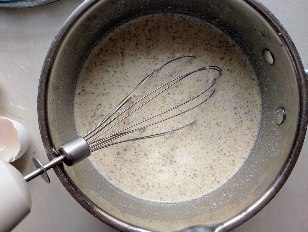 Mixing eggs, cream, milk, and spices to make the custard for the bread and butter pudding
