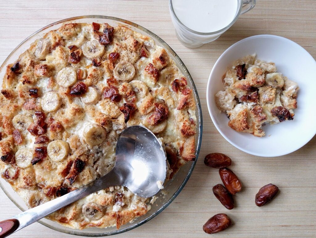 Bread and pudding served from a round casserole dish into bowls with some milk on the side