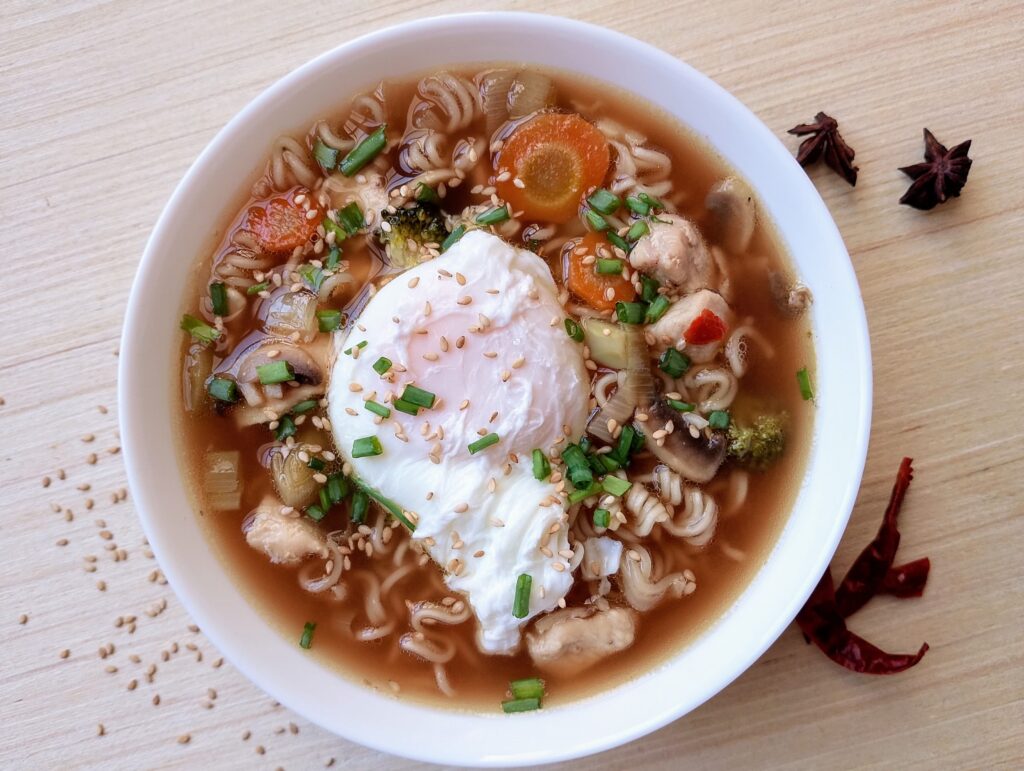 From scrtach Chinese noodle soup served in a bowl with a poached egg, garnished with sliced spring onions and toasted sesame seeds