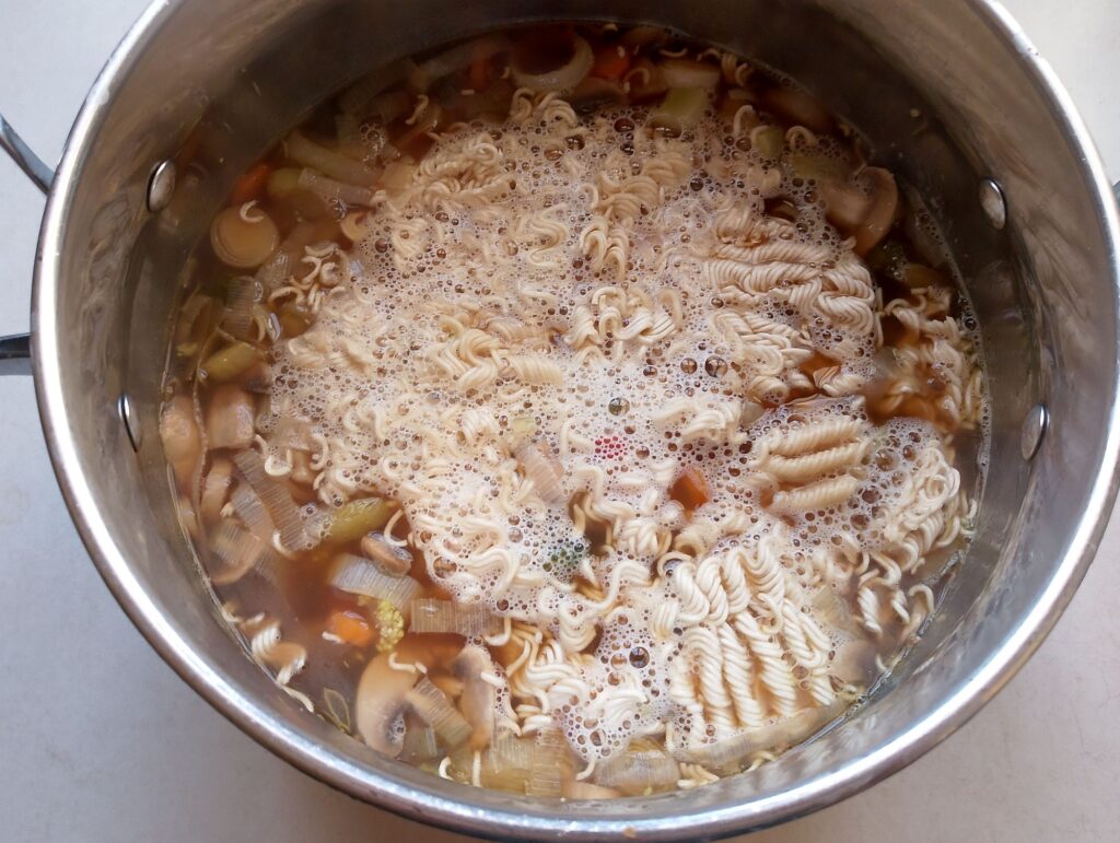 Adding broken up dried egg noodles to the Chinese noodle soup