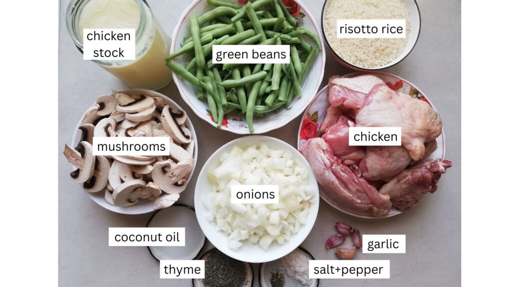 Ingredients for baked risotto assembled in bowls: green beans, risotto rice, chicken legs, chopped onions, garlic, sliced mushrooms, as well as chicken stock in a jar and coconut oil, thyme, salt and pepper in jar lids