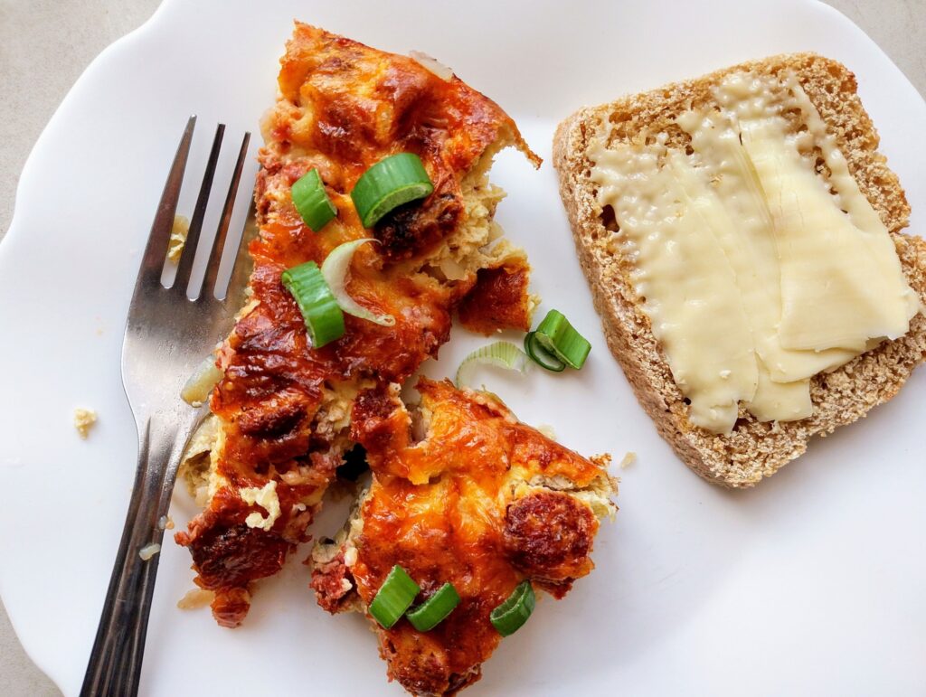 Amish breakfast casserole served on a plate with some buttered sourdough bread on the side