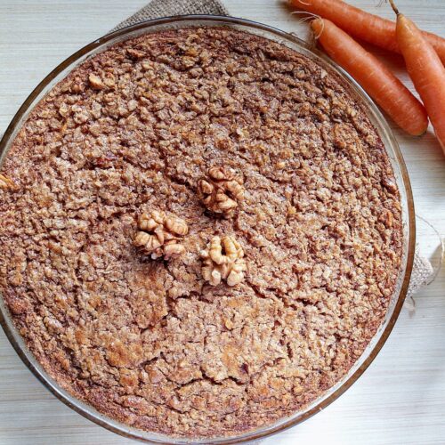 Carrot cake baked oatmeal in a round baking dish with some walnuts on top