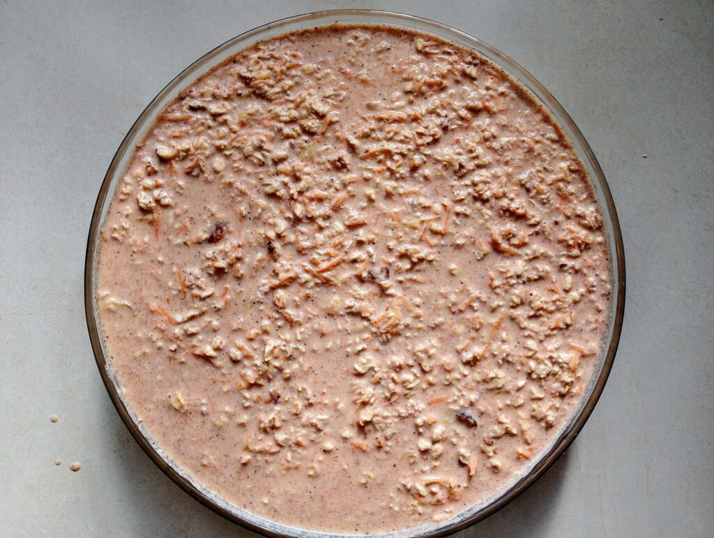 Pouring the carrot cake baked oatmeal ingredients into a round baking dish