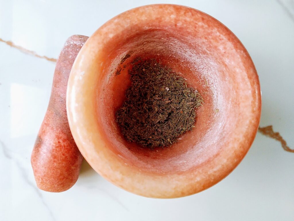 Grinding dried lavender blossoms in a mortar