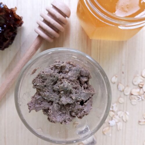 Freshly prepared natural clay and oatmeal face mask with honey in a glass cup