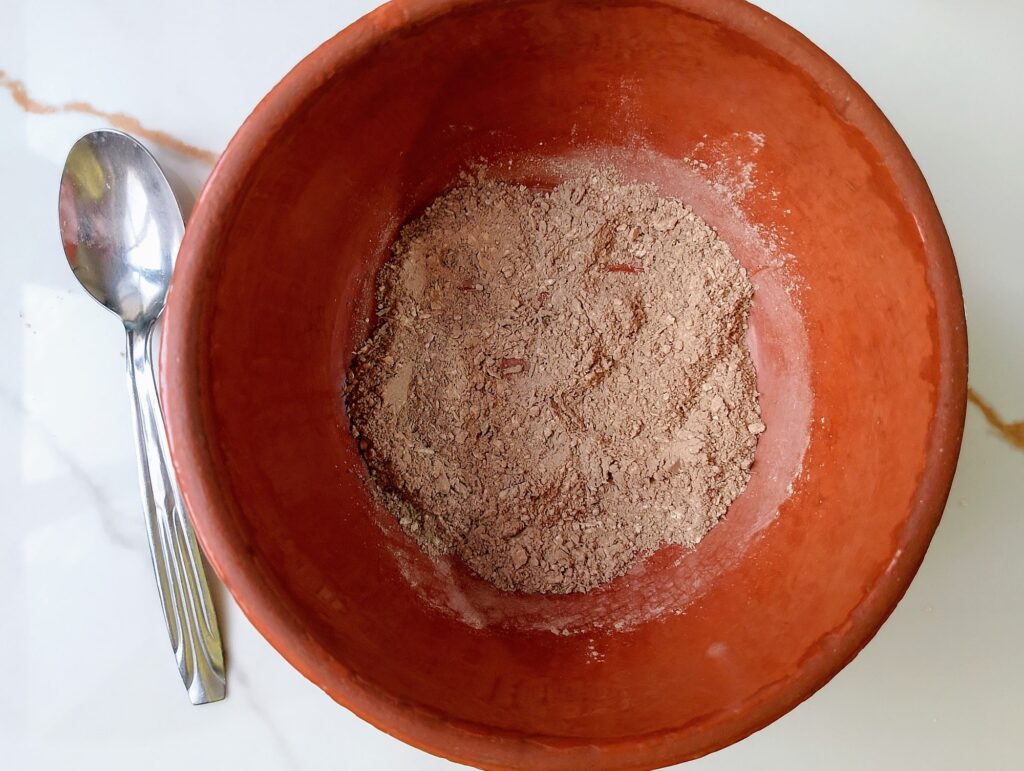 Combining bentonite clay, ground oatmeal, and ground lavender blossoms in a small bowl