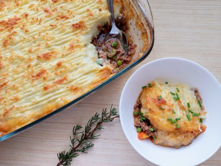 Cottage pie in a casserole dish and a portion of cottage pie in a bowl garnished with chives