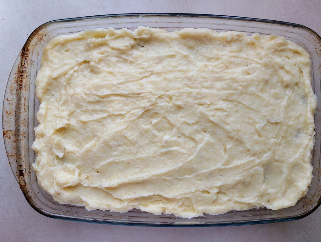 Mashed potato topping spread over the cottage pie filling in the casserole dish