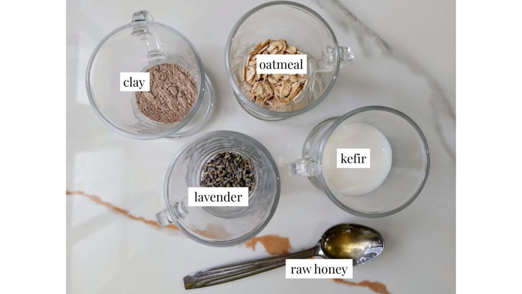 Ingredients for the clay, oatmeal, and honey face mask arranged in cups on a marble countertop