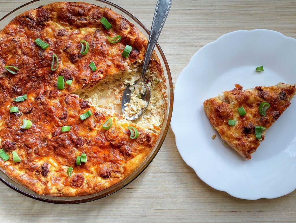 Easy Amish breakfast casserole with sausage on a wooden table with a slice of the casserole taken out onto a plate