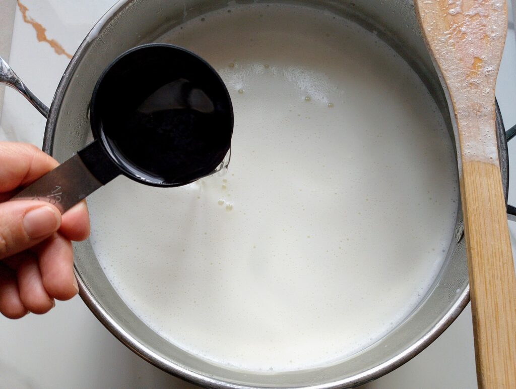 Adding vinegar to the hot raw milk