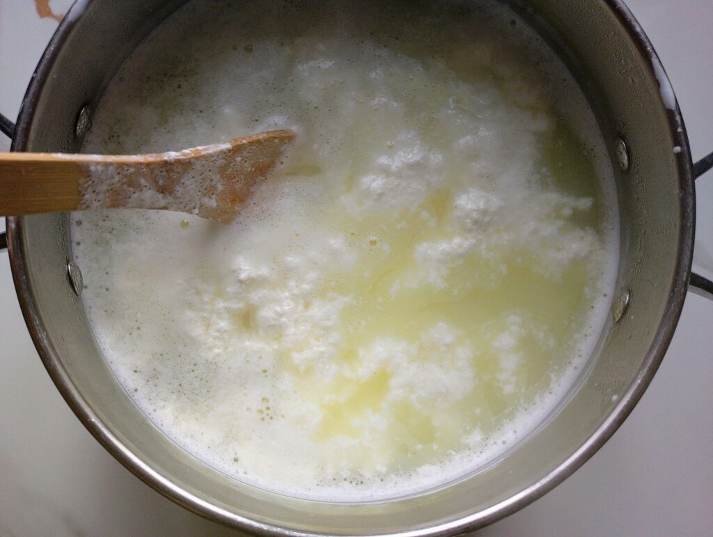 Stirring the vinegar into the hot raw milk to help the formation of curds