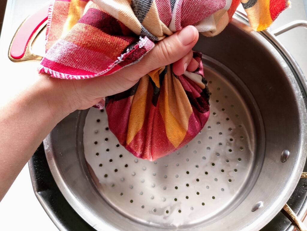 Bundling the curds into the the cheesecloth in preparation for pressing the cheese