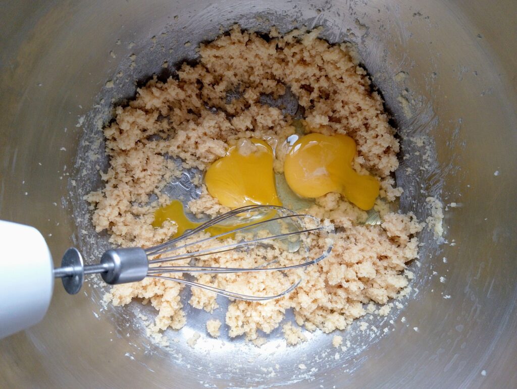 Adding eggs into creamed butter and sugar
