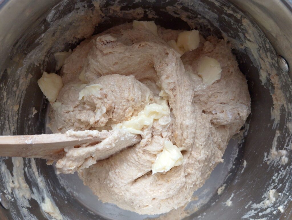 Adding soft cubed butter to the sourdough dinner rolls dough