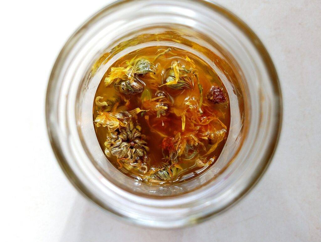 Combining dried calendula petals and olive oil in a glass jar