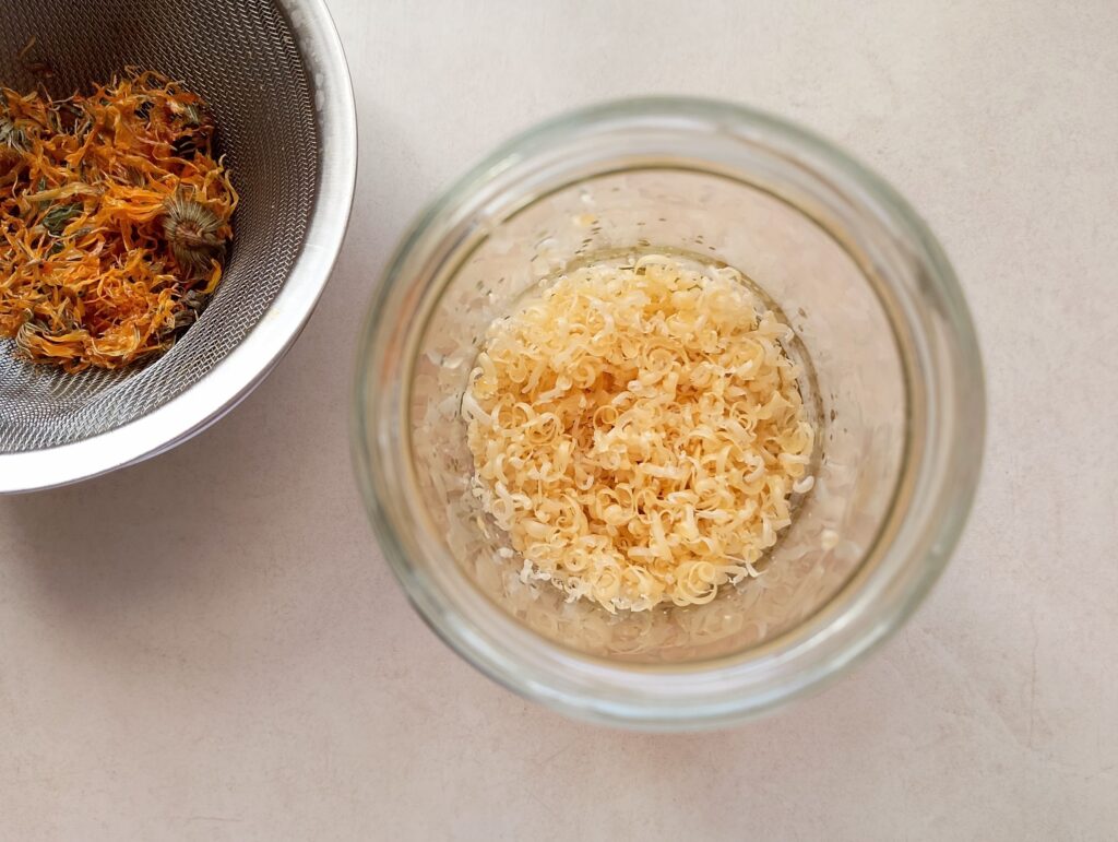 Combining grated beeswax and calendula infused olive oil in a glass jar