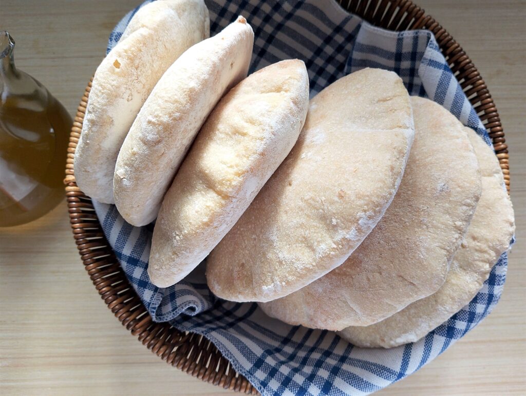 Sourdough pita bread in a basket lined with a tea towel