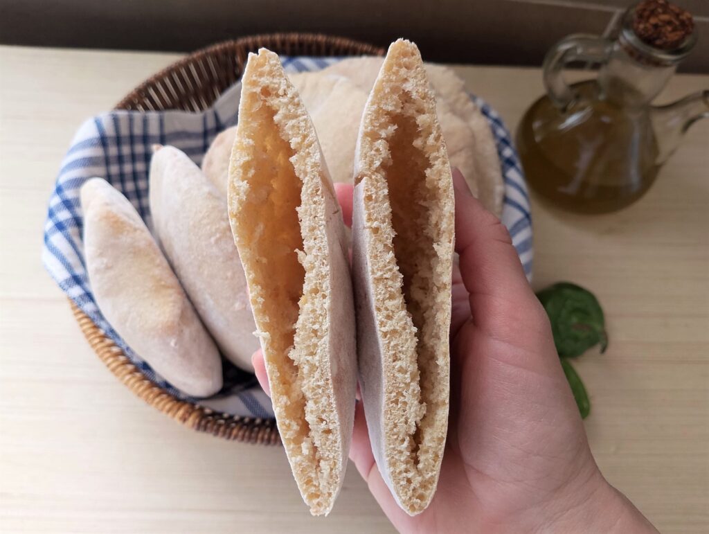 Woman showing sourdough pita bread cut in half to show the pocket inside