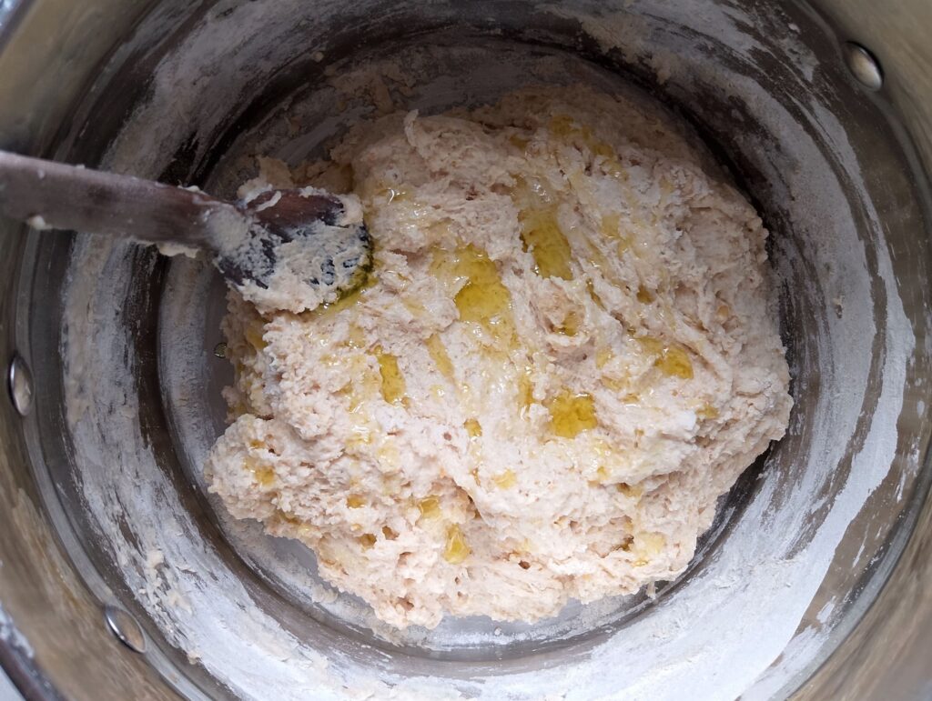 Drizzling olive oil onto the pita bread dough