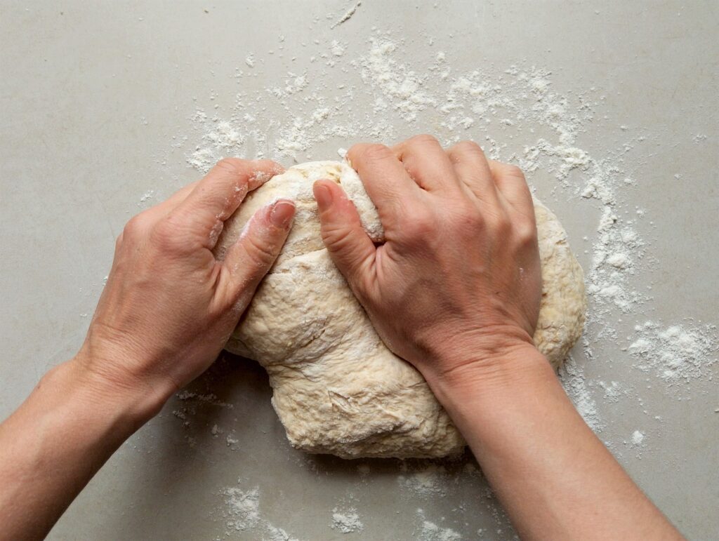 Kneading the dough for sourdough pita bread on a lightly floured counter