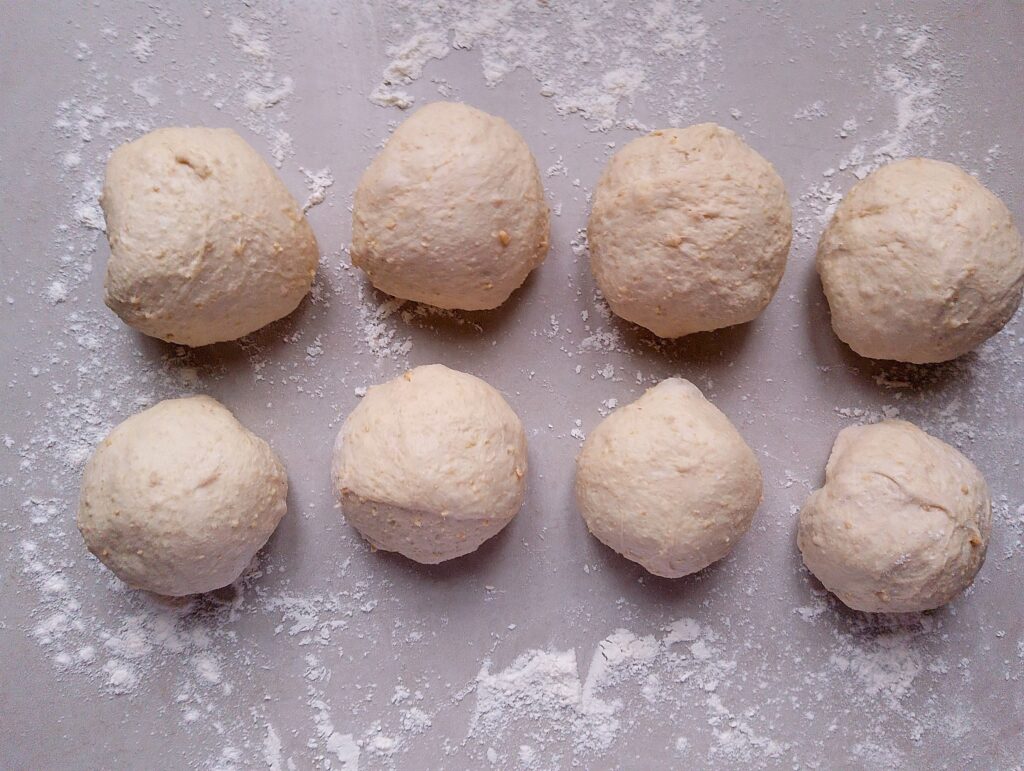 Shaping the dough pieces into balls by tucking in the ends