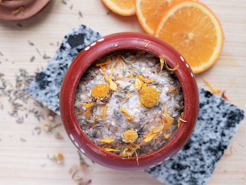 Homemade herbal bath salts in a round clay container