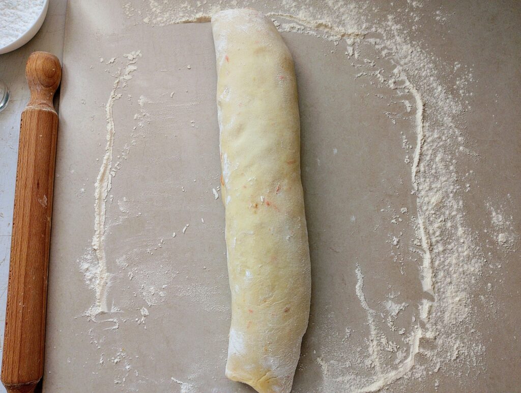 Rolling up the orange cinnamon rolls dough into a log