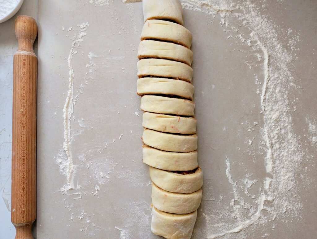 Slicing the roll of dough into 12 rolls