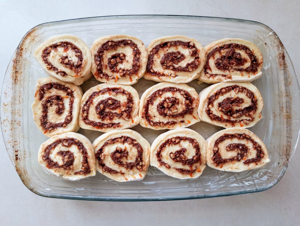 Placing cinnamon rolls in an oiled baking dish for second rise
