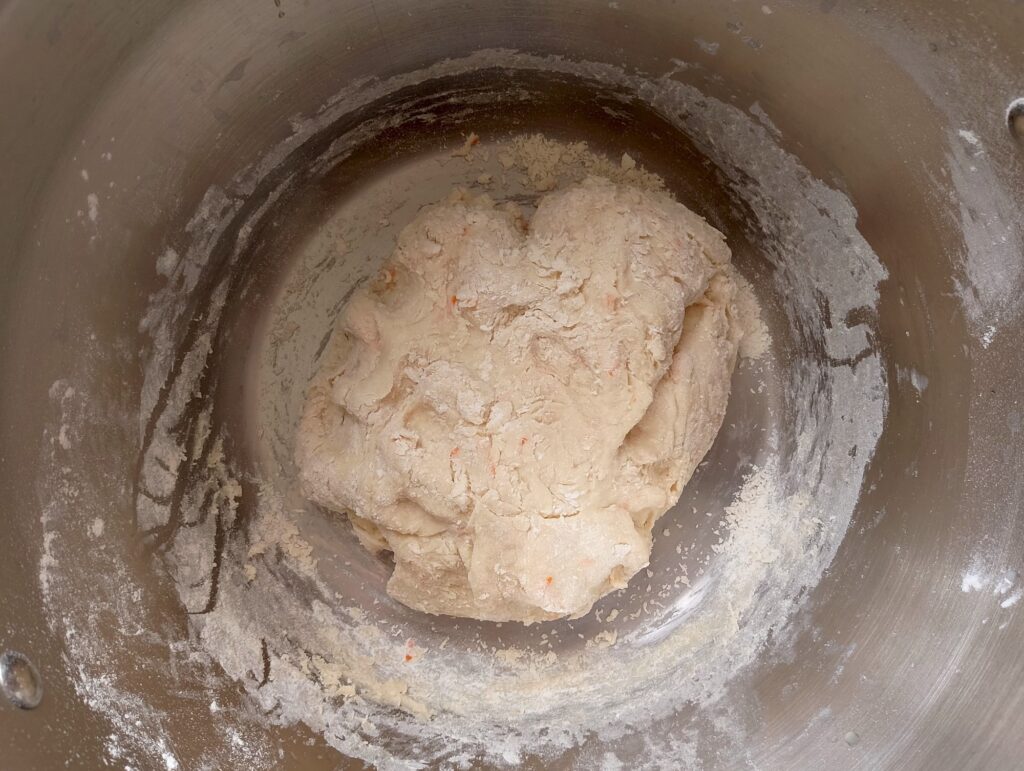 Adding flour to the wet ingredients for cinnamon rolls until soft dough forms