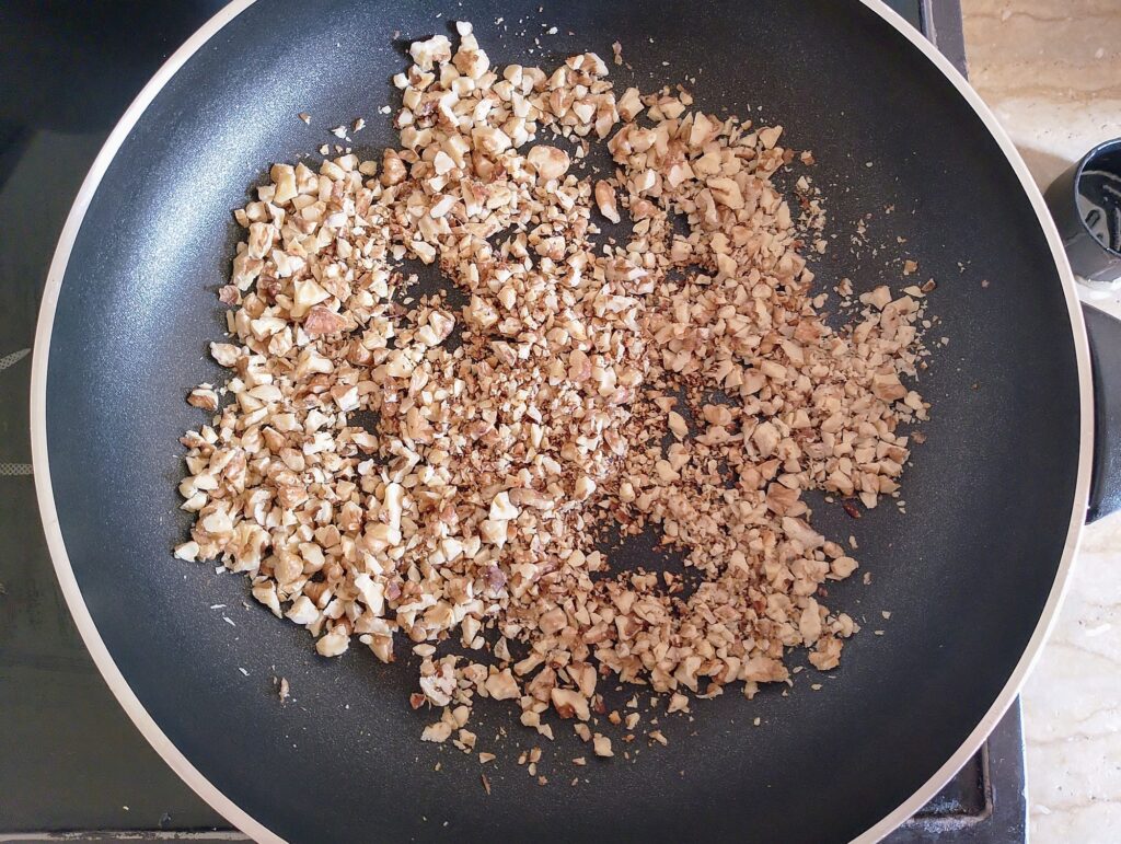 Toasting walnuts for orange cinnamon rolls in a dry skillet