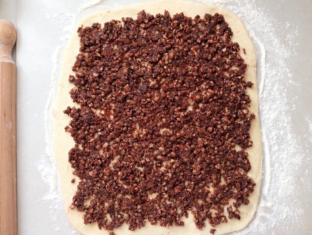 Spreadingthe filling on the rolled out cinnamon rolls dough