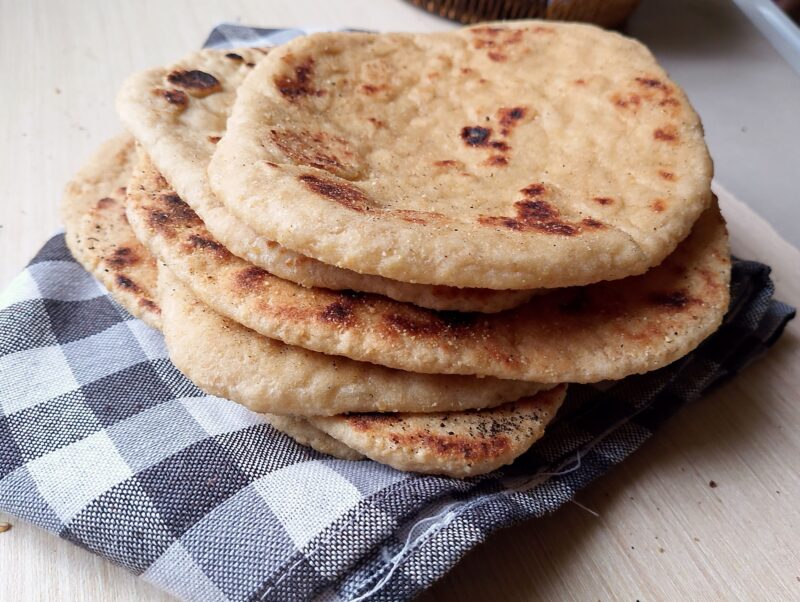 Sourdough naan flatbreads stacked on a tea towel